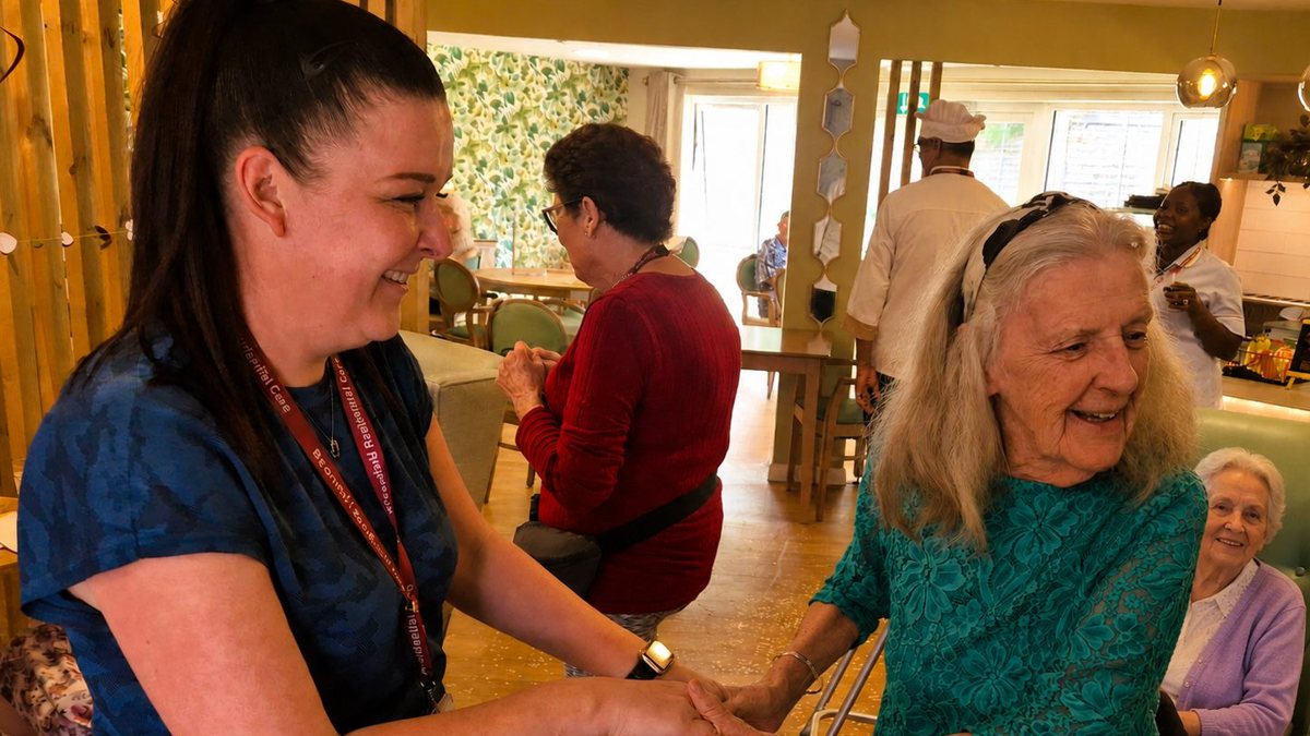 A carer dancing hand in hand with a resident at Broomfield